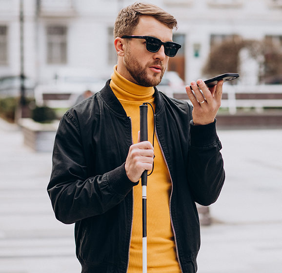 Young blinded man using phone and sending voice message